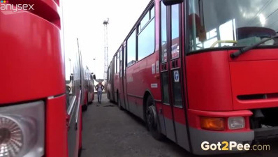 Blond haired filthy cutie looks happy pissing between two big buses