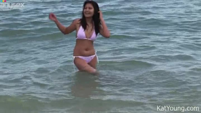 Happy smiling Asian brunette swims in the ocean and poses in her bikini