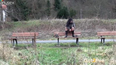 Raven haired petite babe sits on bench and pisses