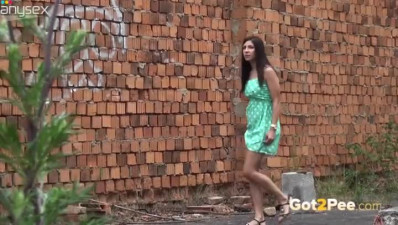 Pretty brunette chick in green spotted dress pisses in the mid of the street