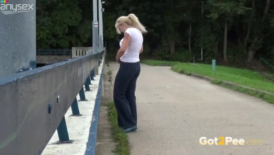 Shy blond haired chick pisses on sidewalk and looks around