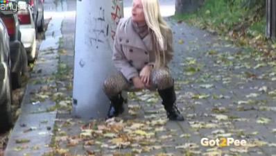 Lusty blond MILF in autumn coat pisses in the mid of the street