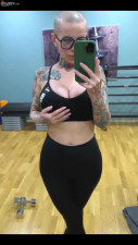 Bald headed MILF with tattooed body masturbates pussy in the gym